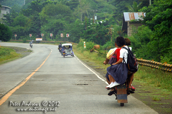 Three children off to school on the back of a motorbike. Along the highway to Kidapawan City, Davao del Sur Province, Mindanao, Philippines. Photo copyright Peter Andrews, Outimage Australia.