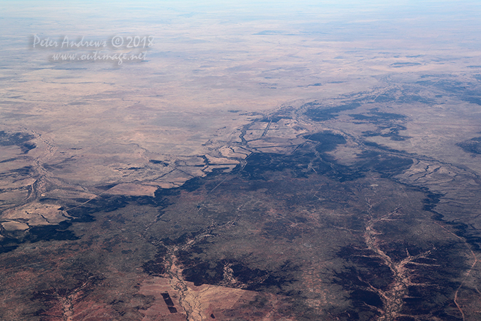 Fence-lines and dirt tracks scar the landscape. Looking towards the Hughenden Muttaburra Road, Outback Queensland. 21°05'59.1"S 144°30'06.0"E. High altitude shots from a flight between Sydney Australia and Manila, Philippines.