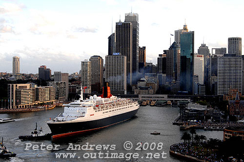 Queen Elizabeth II moving astern into Circular Quay where crowds line the foreshore.