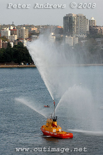 The fire tug Ted Noffs with 3 water jets working stands off Circular Quay to escort Queen Elizabeth 2 out of Sydney for the last time.