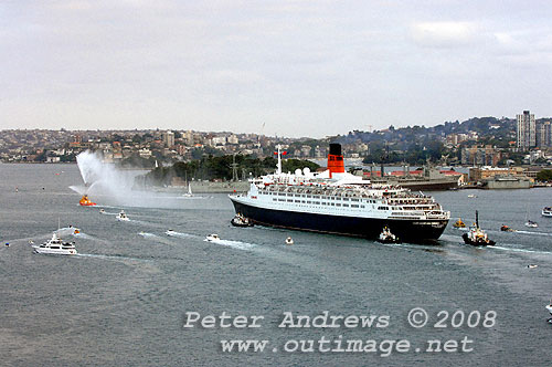 With escort from the fire tug Ted Noffs, Queen Elizabeth 2 steaming out of Sydney Harbour for the last time after 30 years service for Cunard.
