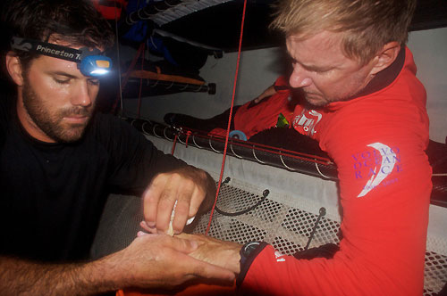 Shannon Falcone tends to PUMA Ocean Racing skipper Ken Read's finger after he got his finger trapped in a titanium block, on leg 4 of the Volvo Ocean Race, from Singapore to Qingdao, China. Photo copyright Rick Deppe / PUMA Ocean Racing / Volvo Ocean Race.