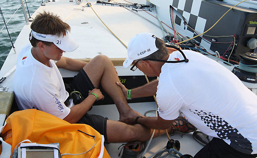 Bowman Michael Pammenter's injured foot is seen to by Roger Nilson, at the start of leg 6 of the Volvo Ocean Race, from Rio de Janeiro to Boston. Photo copyright Anton Paz / Telefonica Black / Volvo Ocean Race.